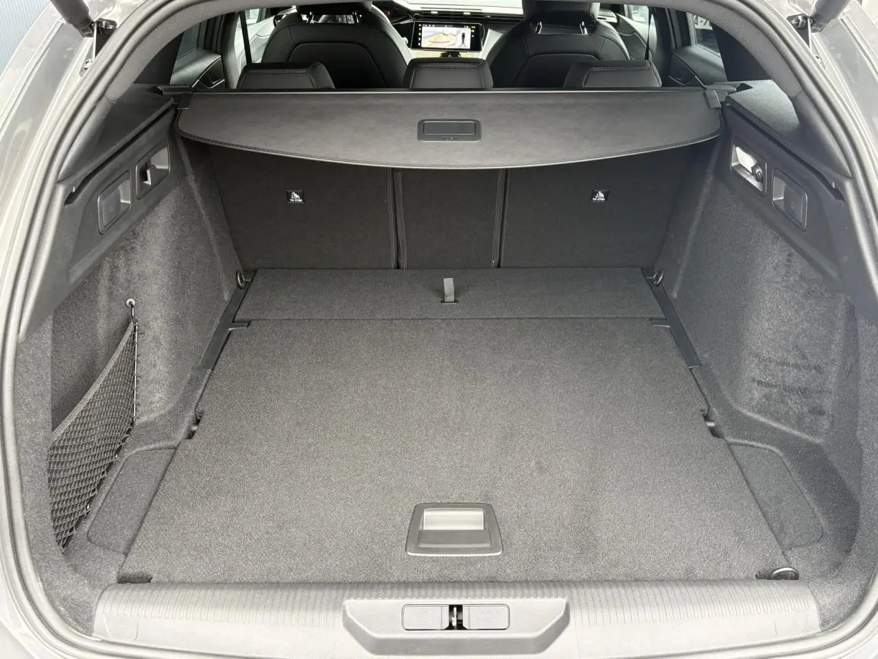Coffre spacieux de la Peugeot 308 SW gris Sélénium, vue arrière avec plancher modulable et filet latéral.