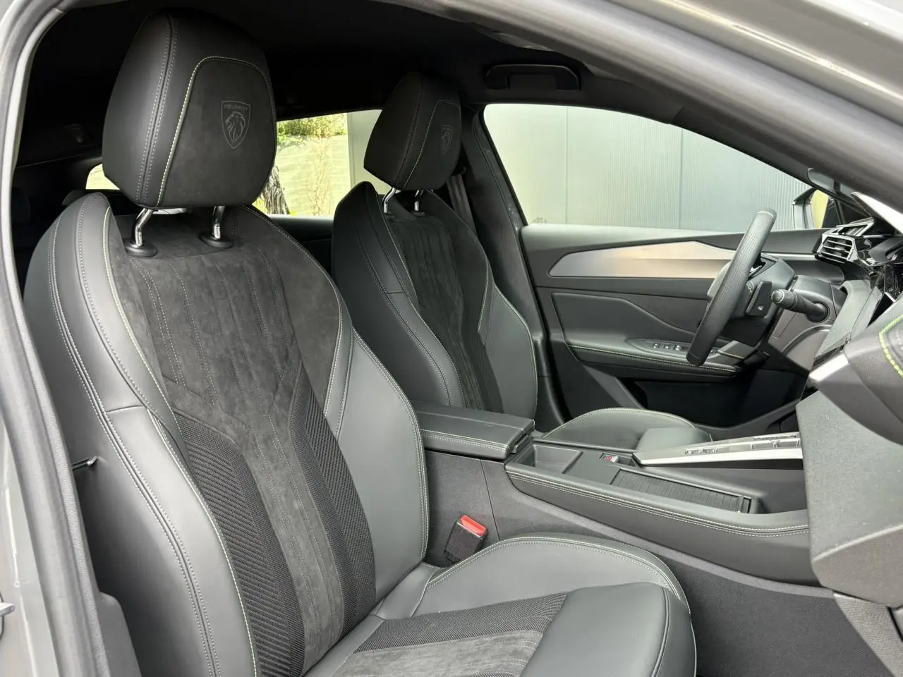 Vue intérieure côté conducteur du Peugeot 308 SW gris Sélénium, mettant en valeur les sièges Alcantara noirs et le volant compact GT.