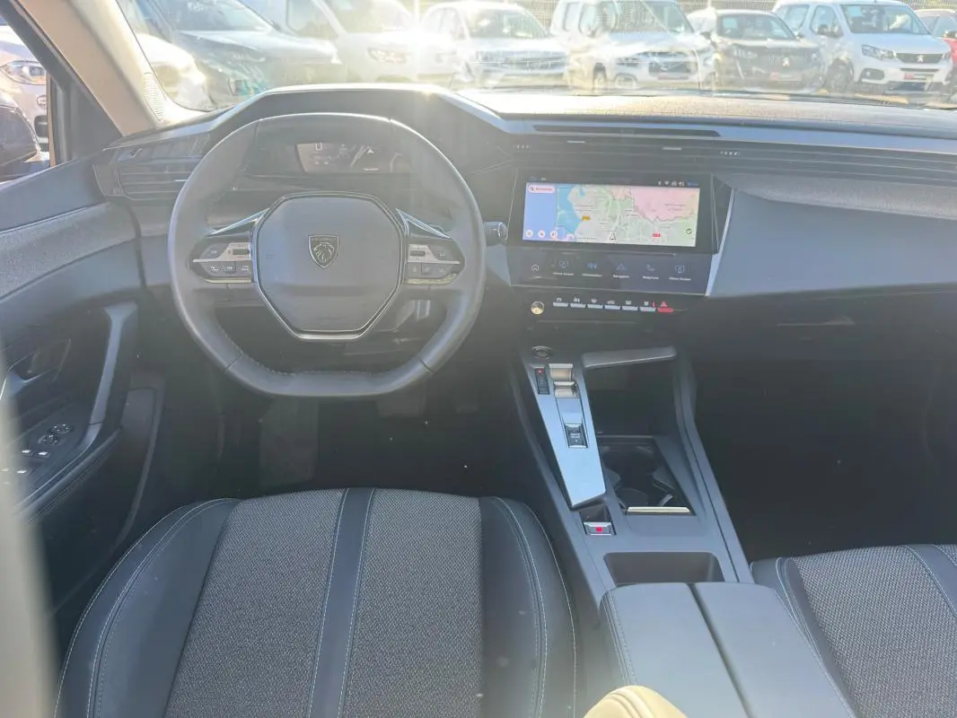 Vue intérieure avant du Peugeot 408 Hybrid 145 e-DCS6 Allure 2025, volant compact et écran tactile central visible.