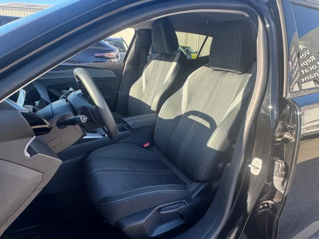 Vue intérieure côté conducteur du Peugeot 408 Hybrid 145 Allure 2025 noir, mettant en valeur les sièges et le volant.