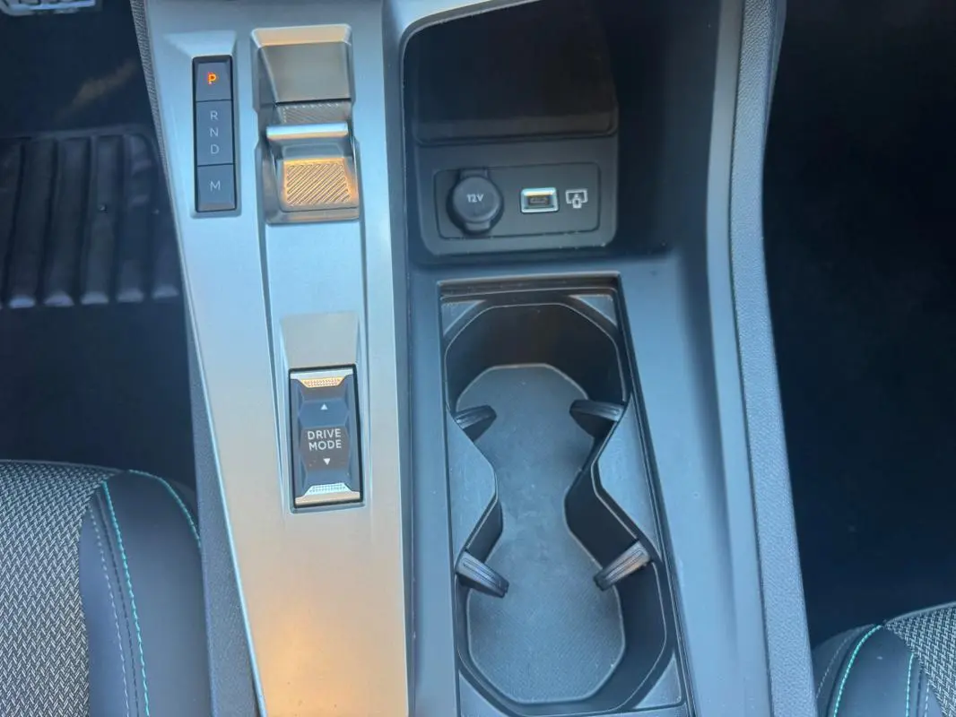 Vue plongeante sur la console centrale noire du Peugeot 408 Hybrid 145 e-DCS6 Allure 2025 avec sélecteur de boîte auto et porte-gobelets.