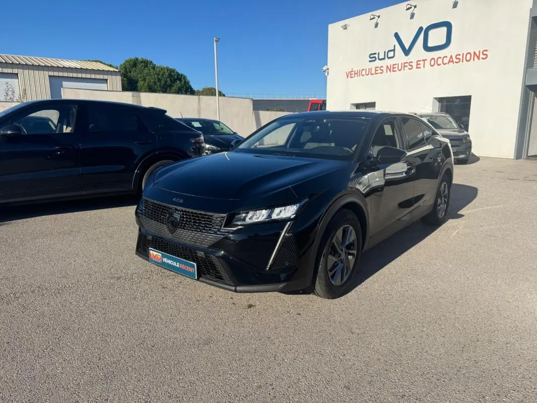 PEUGEOT 408 Hybrid 145 e-DCS6 Allure noir en 3/4 avant droit sur parking devant un bâtiment sud VO.
