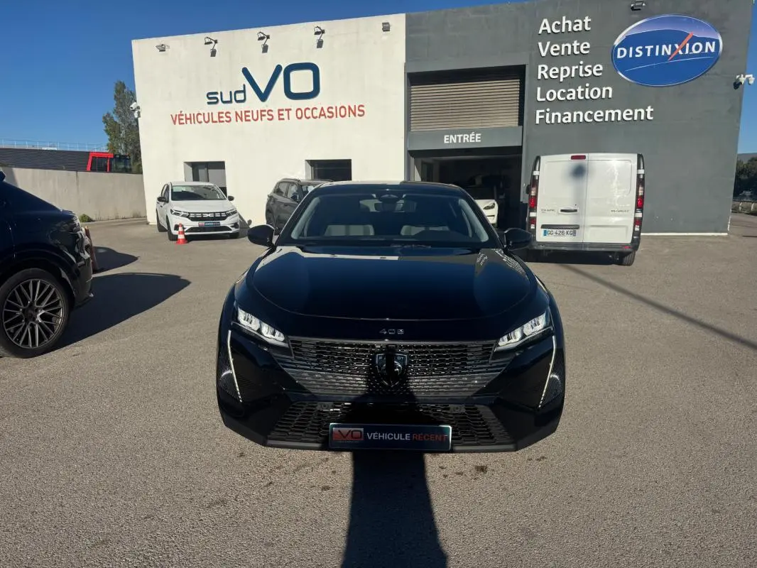PEUGEOT 408 Hybrid 145 e-DCS6 Allure noir vu de face, avec calandre distinctive et phares LED allumés.