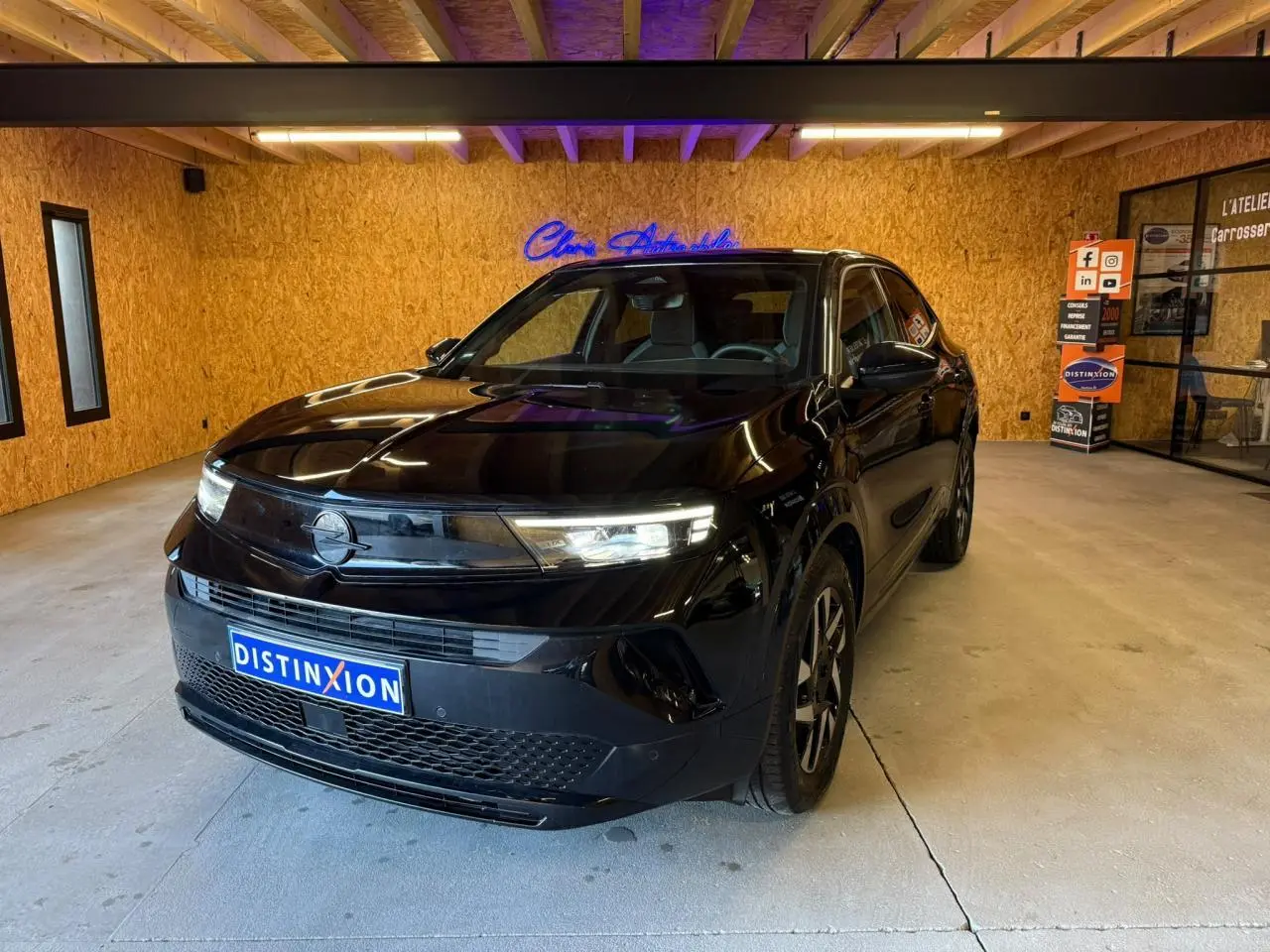 Opel Mokka noir vue 3/4 avant droit en intérieur, avec calandre Vizor et phares LED allumés.