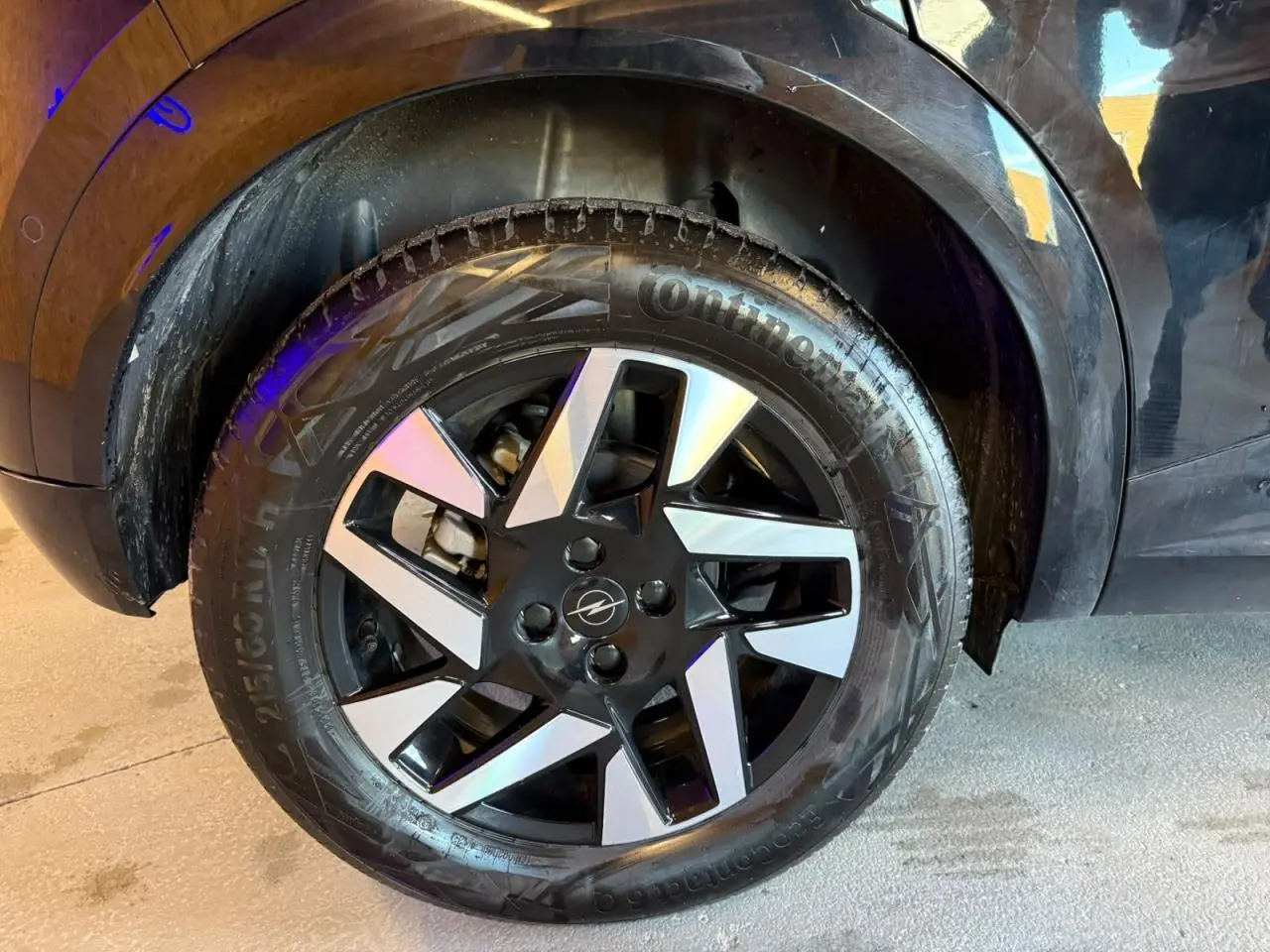 Gros plan sur la roue avant droite noire et argentée d’un Opel Mokka noir avec jante alliage 17 pouces diamantée.