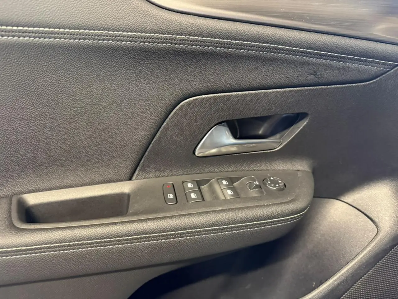 Gros plan sur la porte intérieure côté conducteur noire avec commandes des vitres et poignée chromée du Opel Mokka 2025.