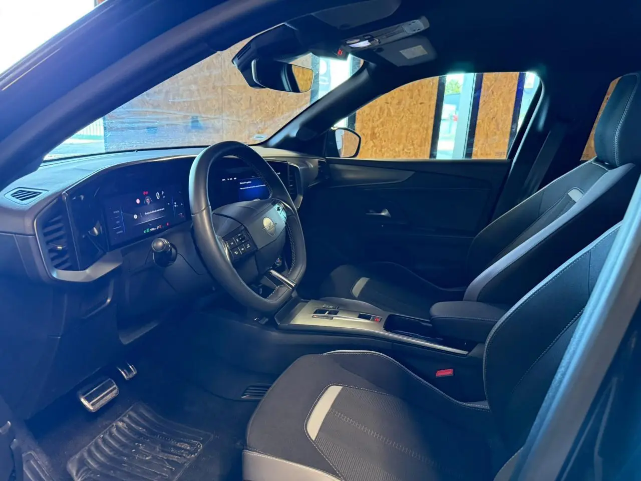 Vue intérieure côté conducteur de l'Opel Mokka 2025, sièges noirs avec inserts gris et tableau de bord numérique.
