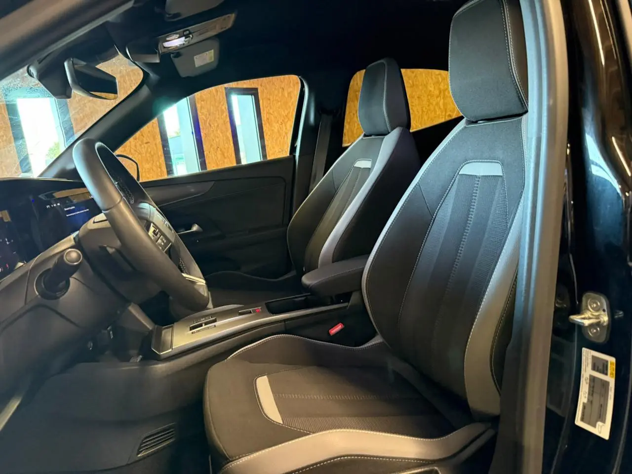 Vue intérieure côté conducteur de l'Opel Mokka noire, sièges tissu noir/gris et volant TEP avec console centrale.
