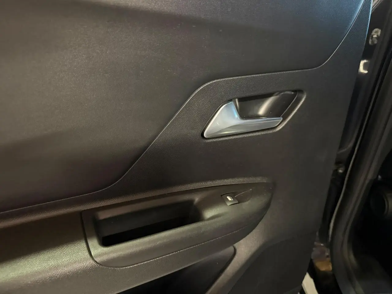 Gros plan sur la porte arrière droite noire de l'Opel Mokka 2025, avec poignée intérieure argentée et bouton de vitre électrique.