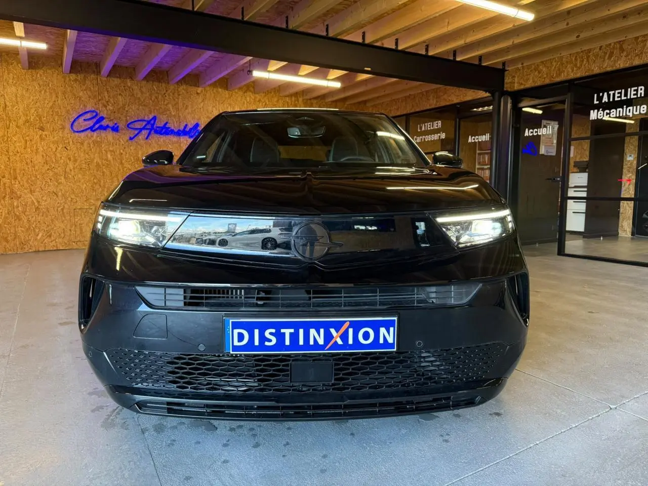Vue avant d’un Opel Mokka noir 2025 avec calandre Vizor et phares LED allumés en intérieur showroom.