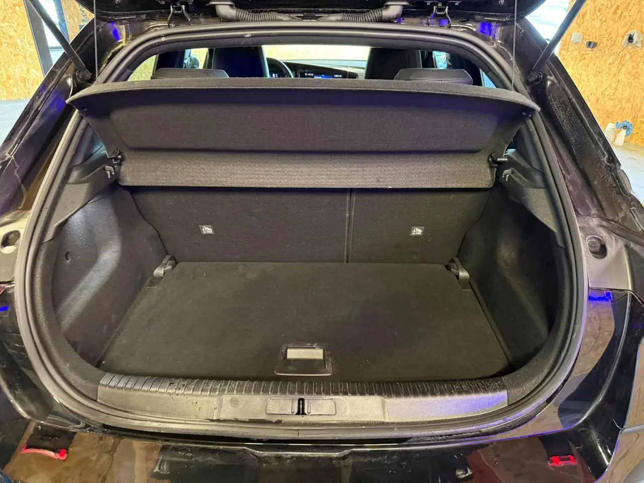 Coffre ouvert vu de l'arrière d'un Opel Mokka noir, montrant l'espace de chargement avec cache-bagages déployé.