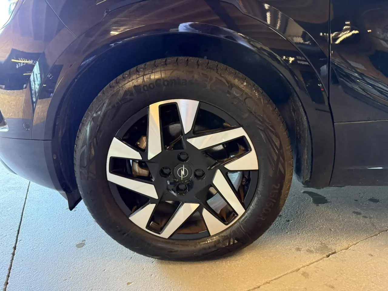 Gros plan sur la roue avant gauche noire d’un Opel Mokka 2025 avec jante alliage diamantée bicolore.