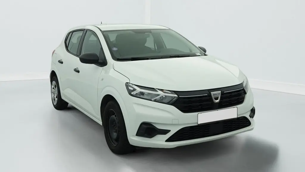 Vue 3/4 avant d'une Dacia Sandero blanche avec calandre noire et jantes tôles 15 pouces.