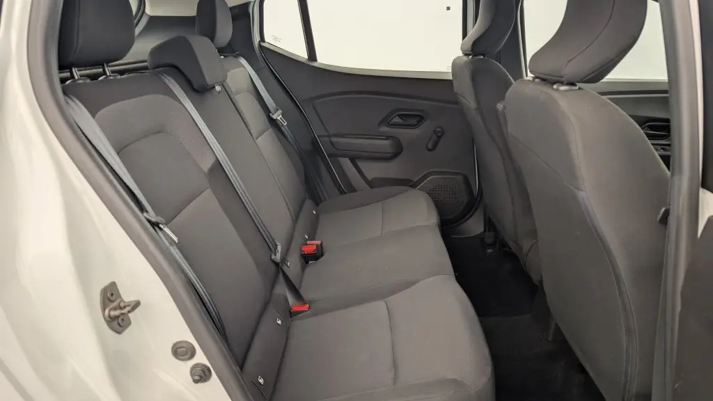 Vue intérieure arrière de la Dacia Sandero blanche 2022, montrant la banquette arrière en tissu gris avec ceintures de sécurité.