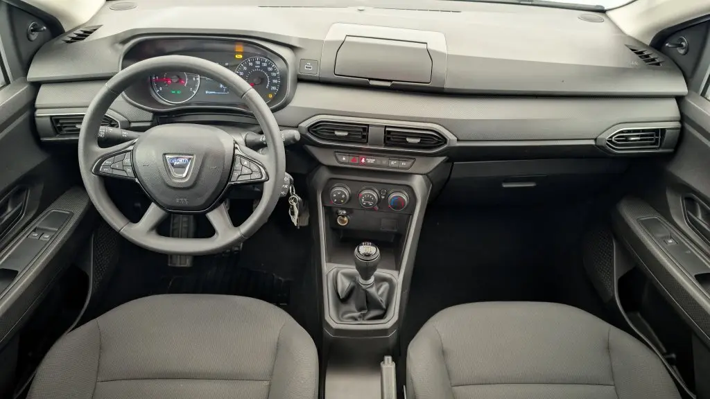 Vue intérieure avant de la Dacia Sandero blanche 2022, tableau de bord et volant avec commandes multifonctions.