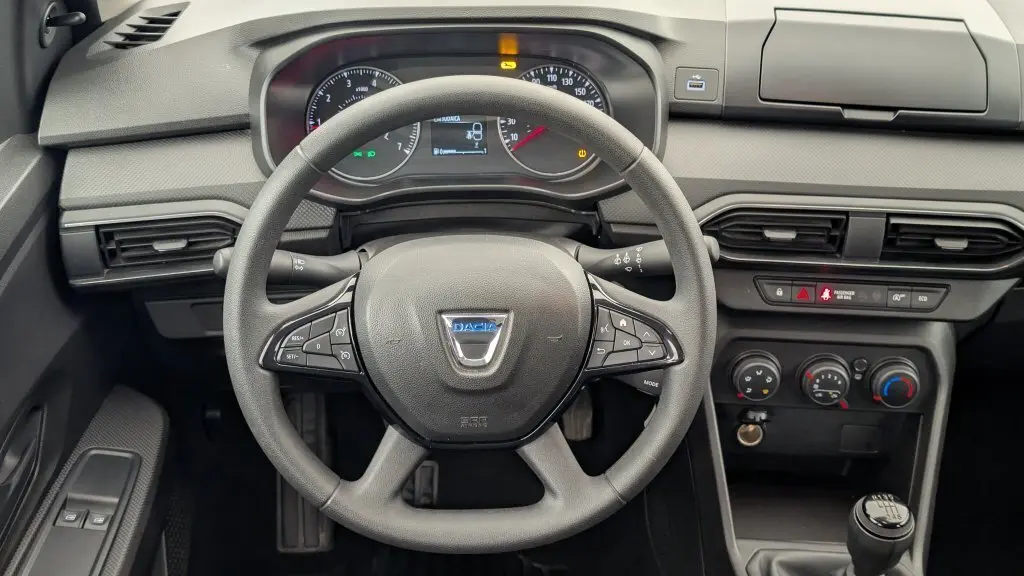 Vue frontale du tableau de bord de la Dacia Sandero 2022, volant multifonction et commandes climatiques visibles.