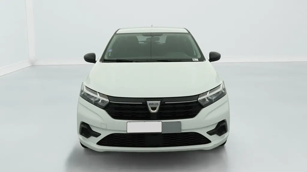 Vue frontale d'une Dacia Sandero blanche avec calandre noire et signature lumineuse en Y à LED visible.