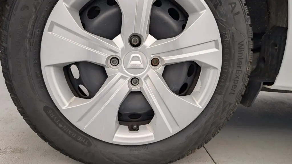 Gros plan sur la roue avant droite de la Dacia Sandero blanche 2022 avec enjoliveur Elma 15 pouces.