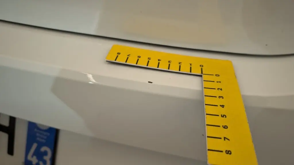 Gros plan sur une petite éclatation de peinture blanche sur le pare-chocs arrière d'une Dacia Sandero ECO-G 100 2022.