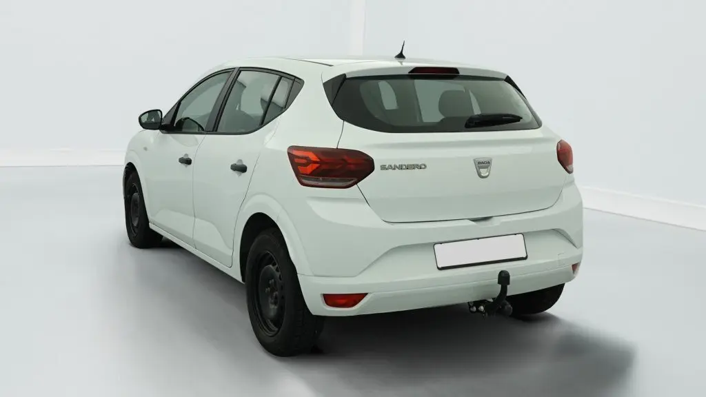Vue 3/4 arrière droite d'une Dacia Sandero blanche avec attelage et feux arrière à signature lumineuse en Y.