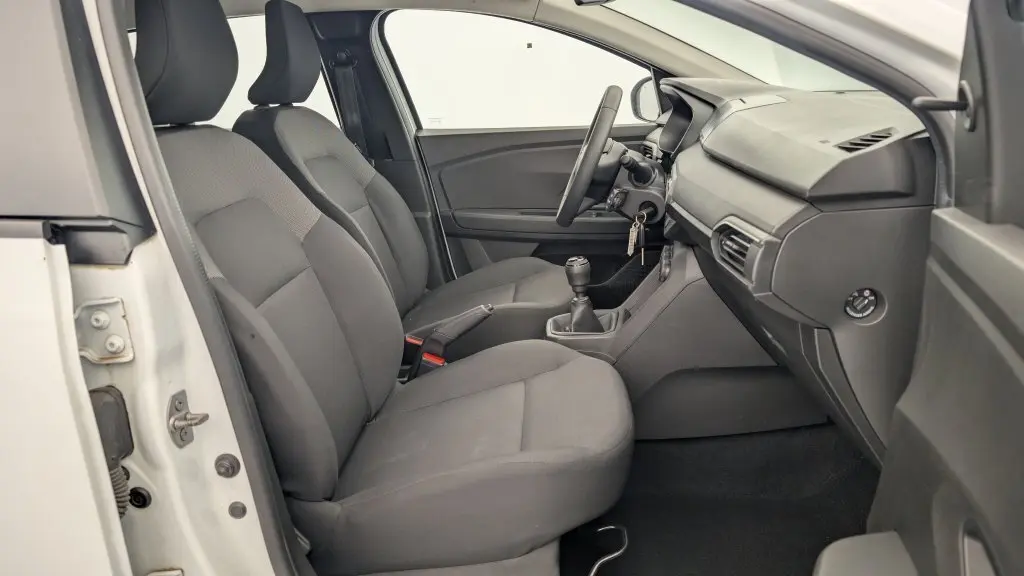 Intérieur côté conducteur de la Dacia Sandero ECO-G 100 2022, sièges gris et tableau de bord simple en vue latérale.