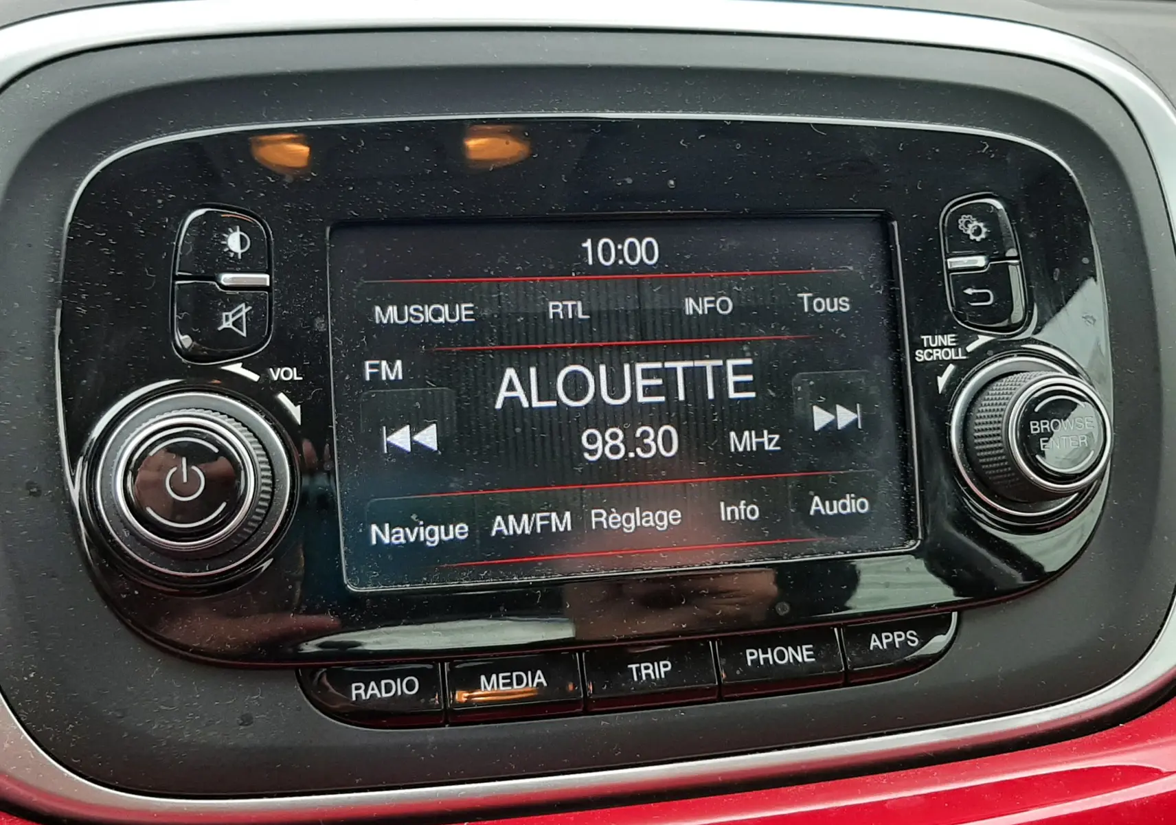 Gros plan sur l'écran multimédia central de la Fiat 500X rouge, affichant la radio FM sur la station Alouette 98.30 MHz.