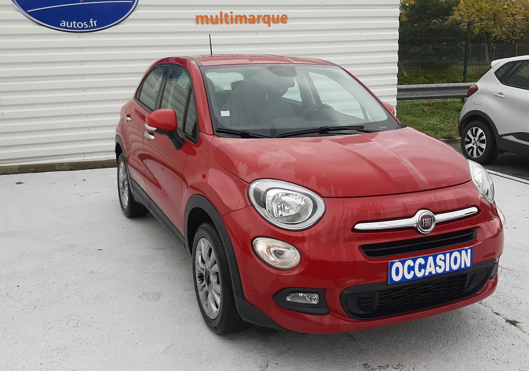 Fiat 500X rouge vue 3/4 avant droit, avec plaque "OCCASION" et logo Distinxion en arrière-plan.