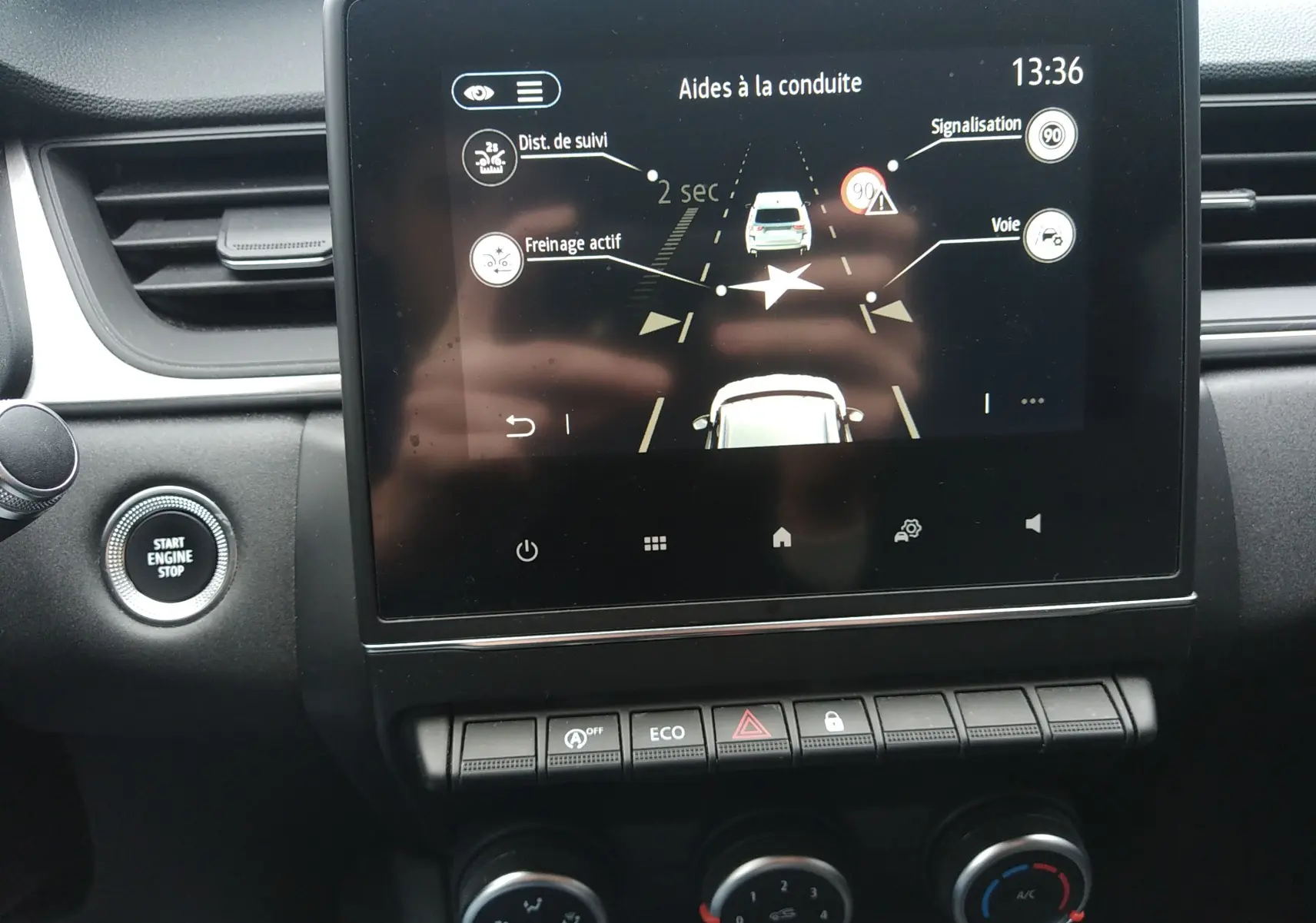 Vue rapprochée de l'écran tactile central du Renault Captur 2021 noir, affichant les aides à la conduite et boutons de commande.