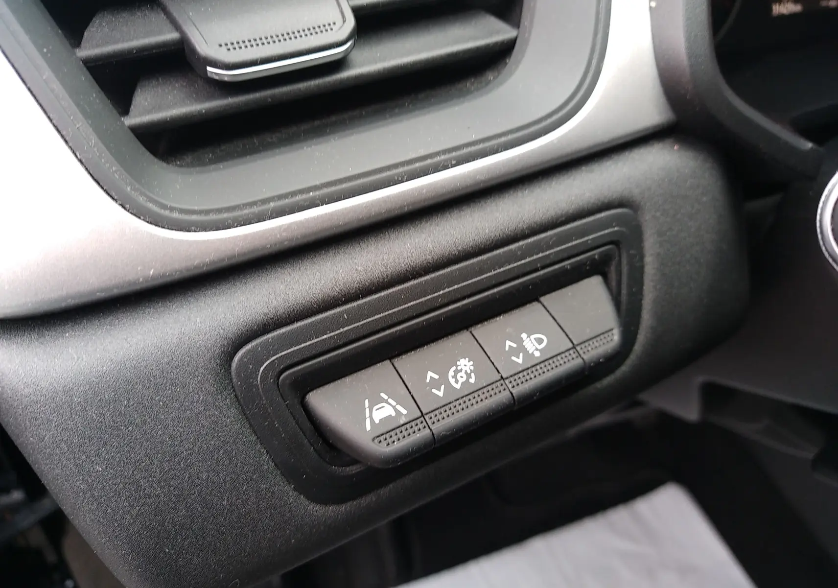 Gros plan sur les boutons de réglage d'assistance et éclairage côté gauche du tableau de bord du Renault Captur noir 2021.