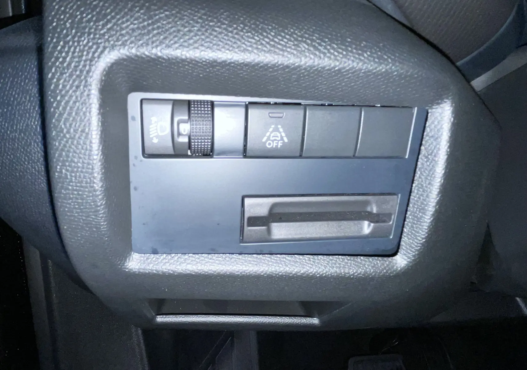 Gros plan sur les commandes de réglage des feux et assistance à la conduite du Citroën C5 Aircross 2024 noir.