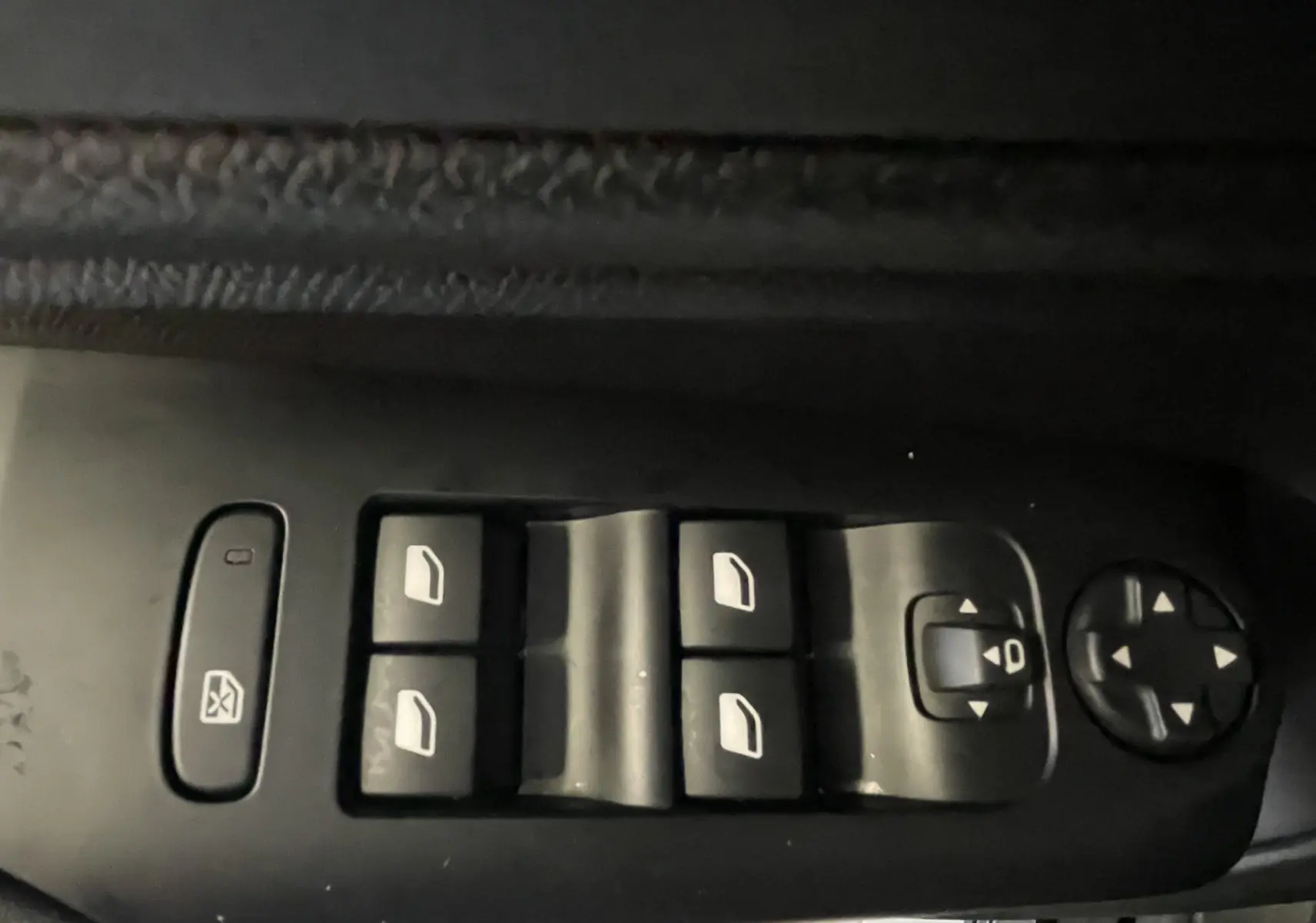 Gros plan sur les commandes des vitres électriques et réglages des rétroviseurs côté conducteur d’un Citroën C5 Aircross noir.