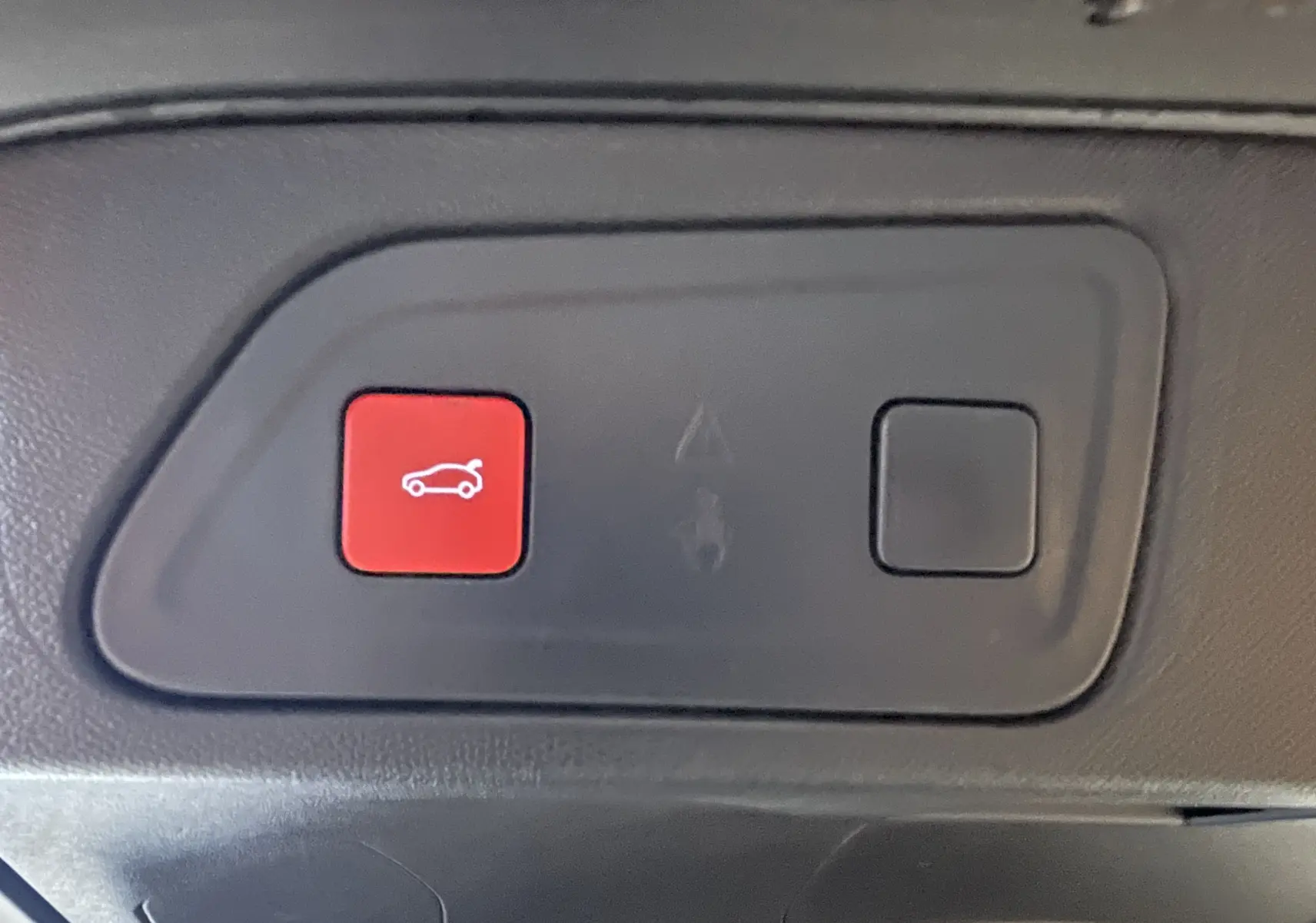 Gros plan sur le bouton rouge d'ouverture du coffre dans l'habitacle du Citroën C5 Aircross noir 2024.