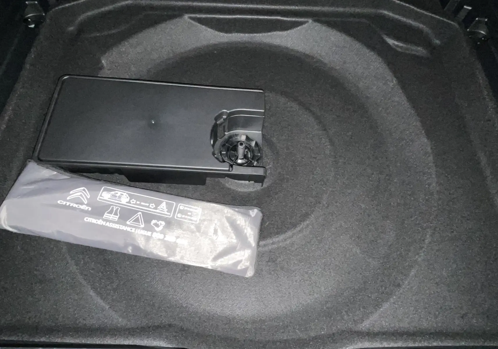 Coffre du Citroën C5 Aircross 2024 noir, vue plongeante sur rangement sous plancher avec kit d’assistance visible.