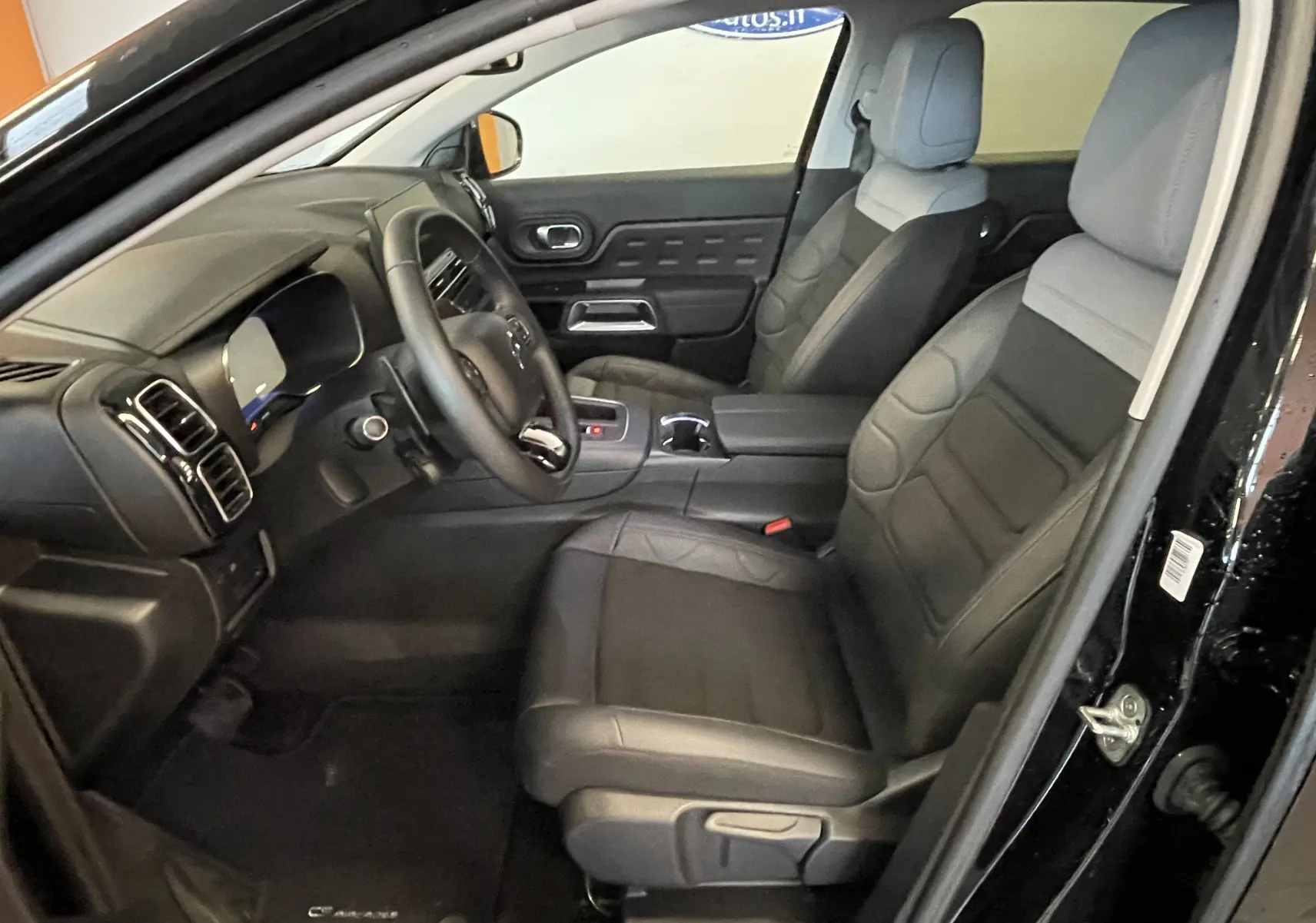 Intérieur avant du Citroën C5 Aircross noir 2024, vue côté conducteur, sièges tissu et cuir gris, volant cuir croûte.