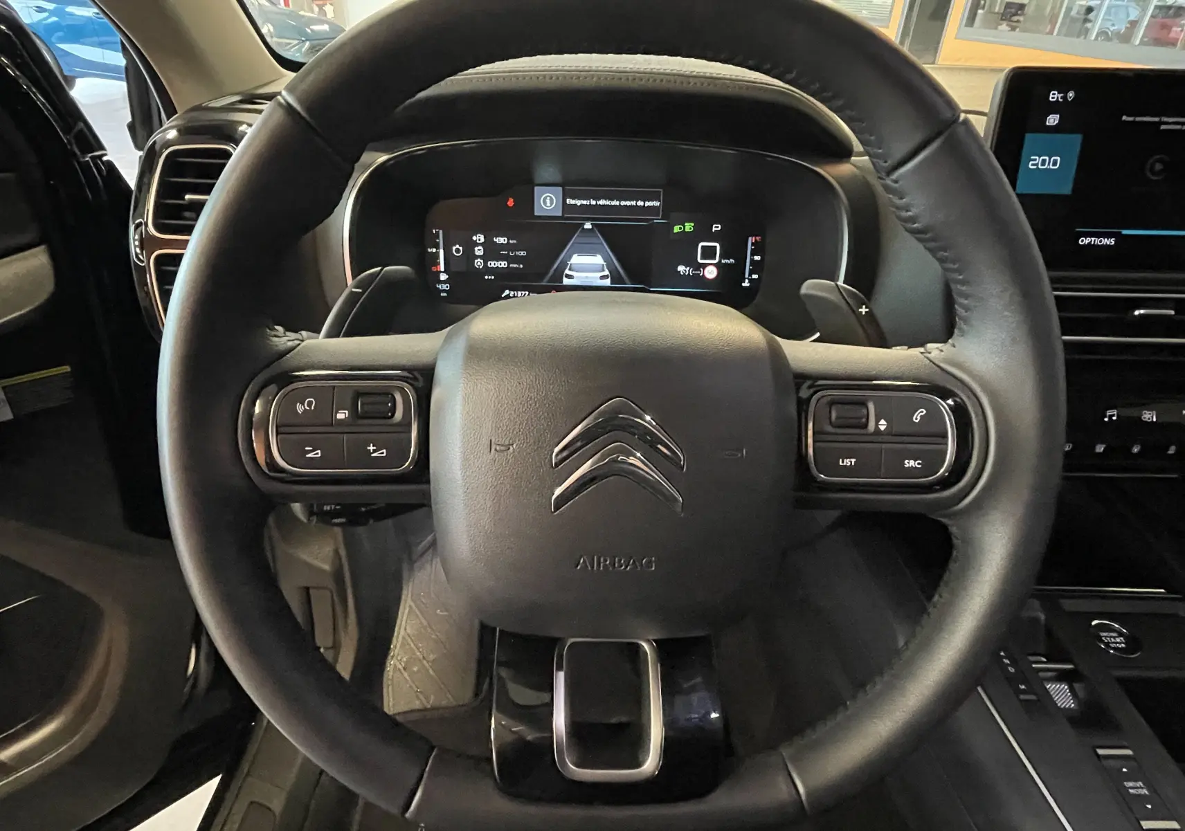 Vue rapprochée du volant en croûte de cuir noir du Citroën C5 Aircross 2024 avec tableau de bord numérique et commandes intégrées.