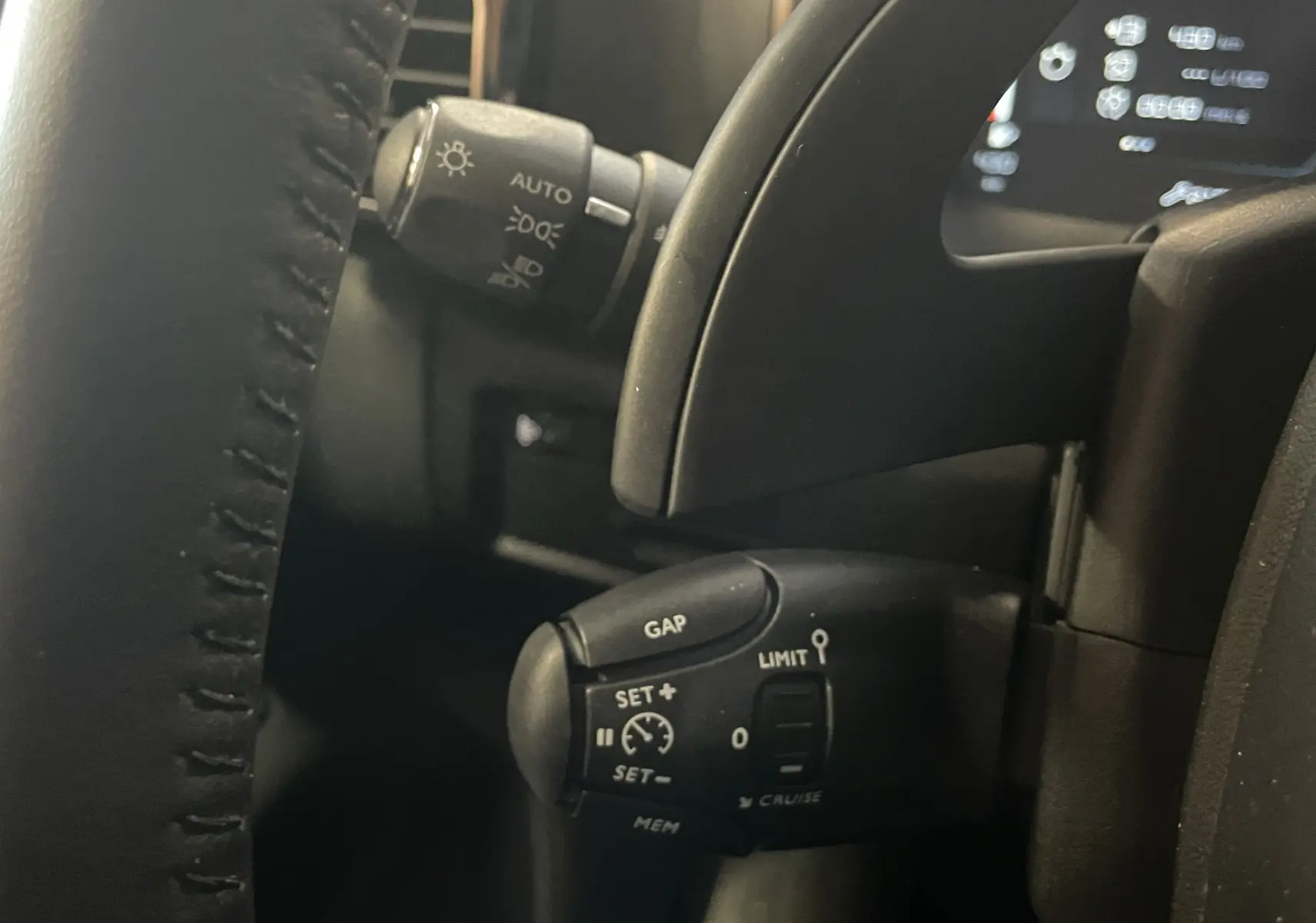 Gros plan sur la commande de régulateur de vitesse à gauche du volant noir du Citroën C5 Aircross 2024.