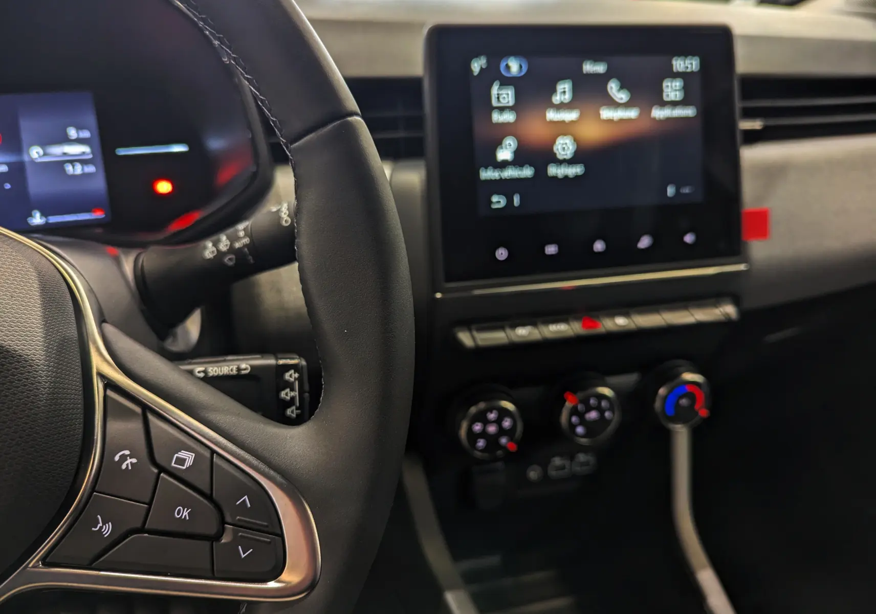 Vue intérieure centrée sur le volant à gauche et l’écran tactile du tableau de bord de la Renault Clio V Gris Rafale.