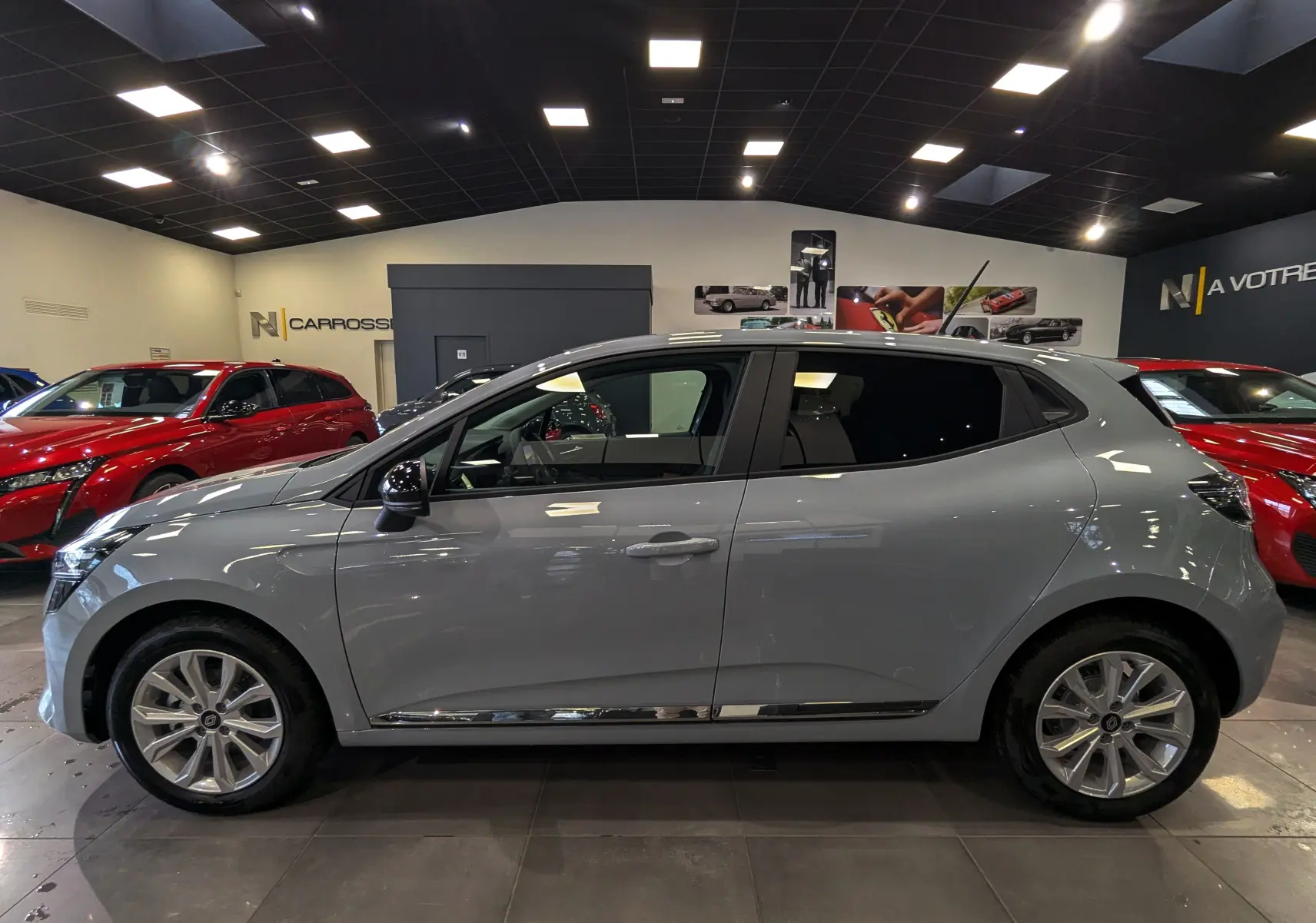 Profil côté gauche de la Renault Clio V gris Rafale 2025 en intérieur, avec jantes alliage et vitres teintées.