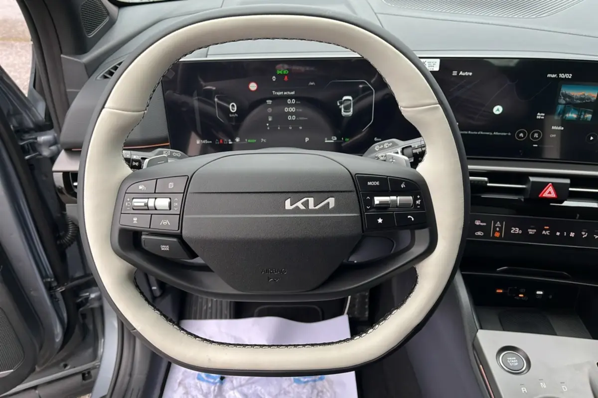 Vue intérieure centrée sur le volant cuir bicolore gris clair et noir du Kia Sportage 2026 avec tableau de bord numérique.