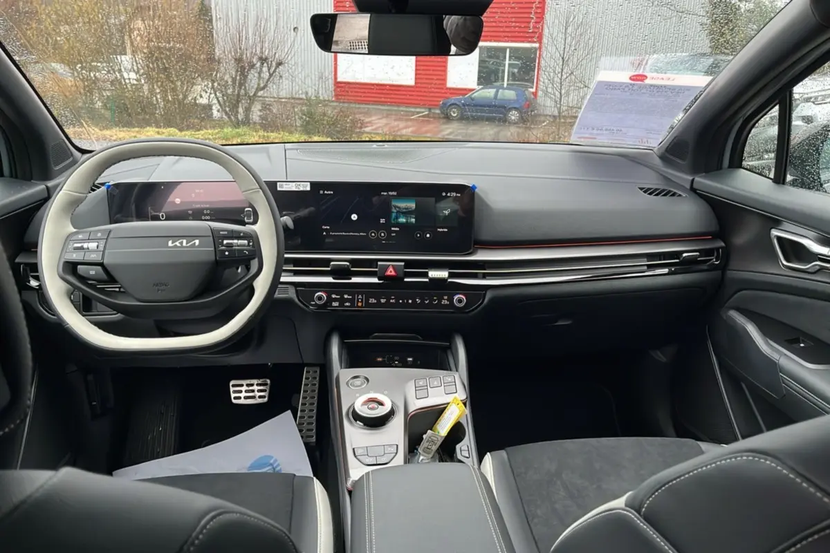 Vue intérieure avant du Kia Sportage 2026, tableau de bord moderne avec écran tactile et volant cuir bicolore.