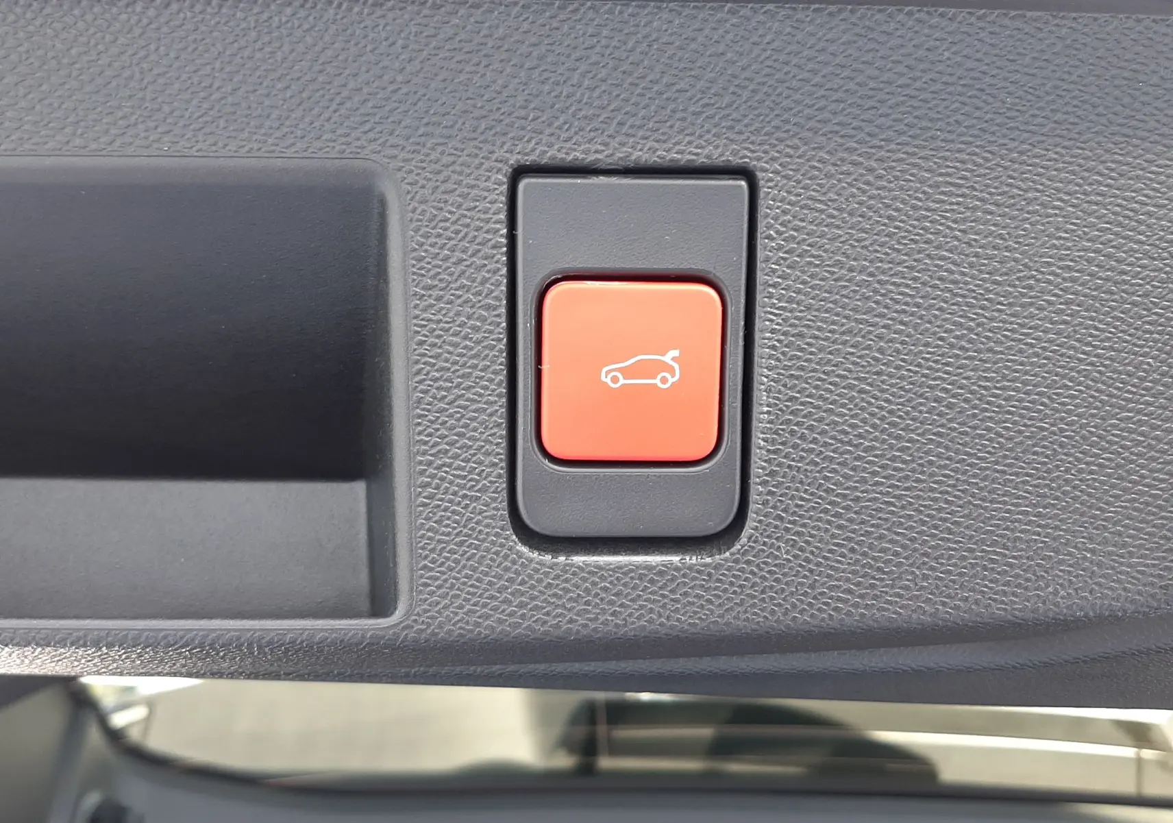 Bouton rouge d'ouverture du coffre sur panneau intérieur gris texturé d'un Citroën C5 Aircross hybride 2026.