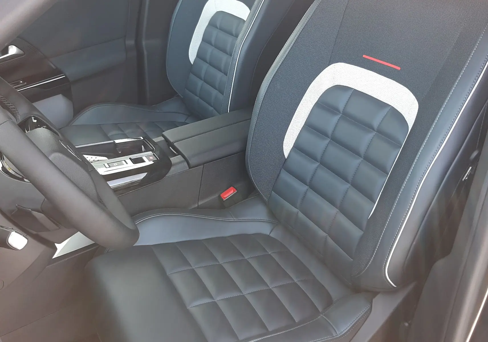 Vue intérieure côté conducteur du Citroën C5 Aircross hybride 2026, sièges noirs avec surpiqûres et détails gris clair.