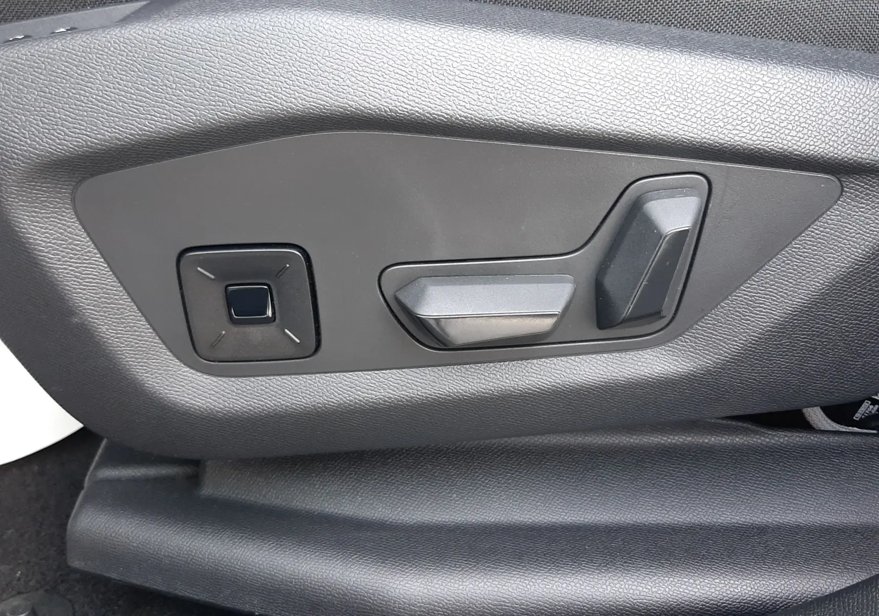 Gros plan sur les commandes électriques de réglage du siège en cuir noir dans une Citroën C5 Aircross hybride gris platinium.