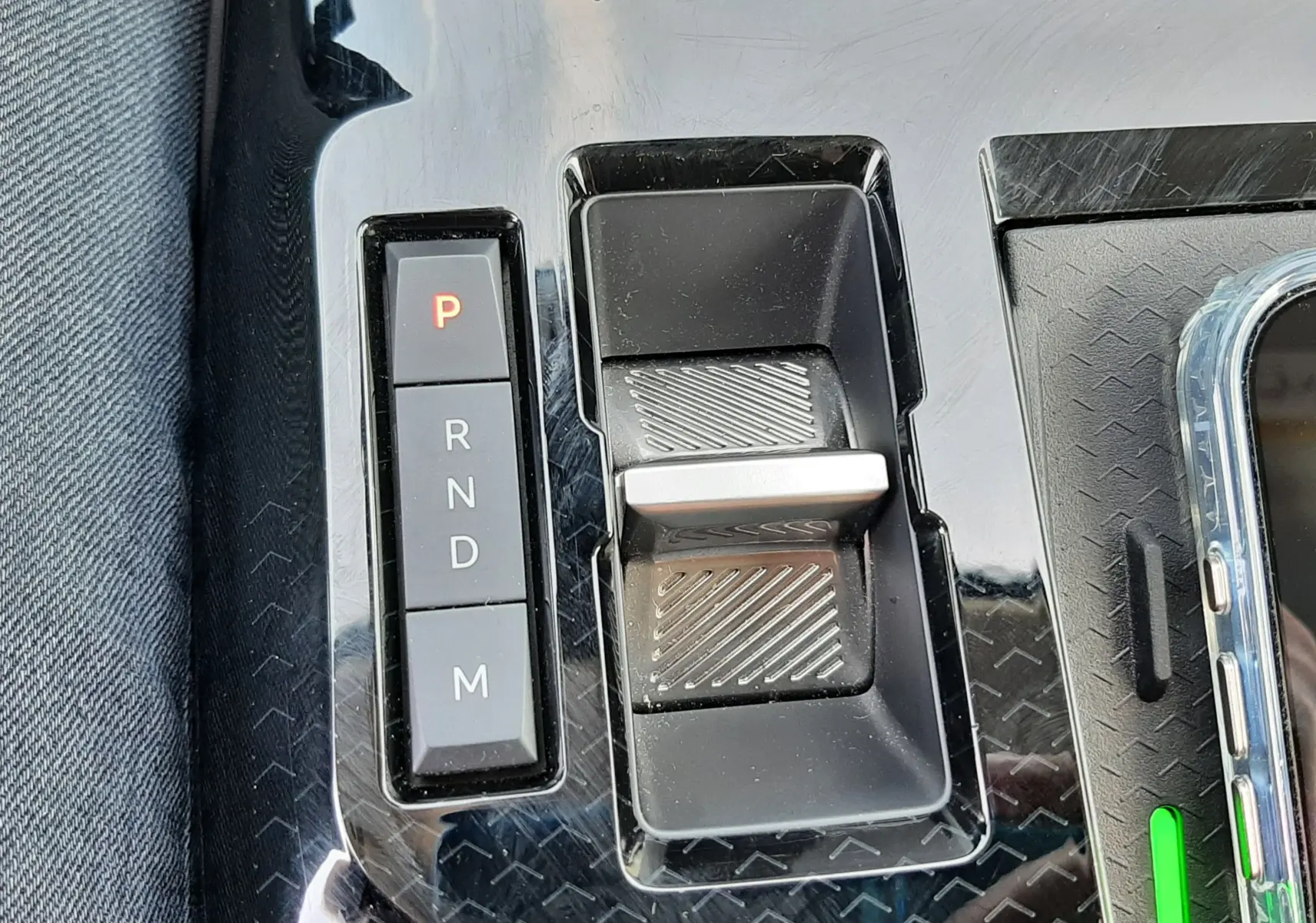 Gros plan sur la console centrale noire brillante du Citroën C5 Aircross hybride avec levier de vitesses électronique et boutons P, R, N, D, M.