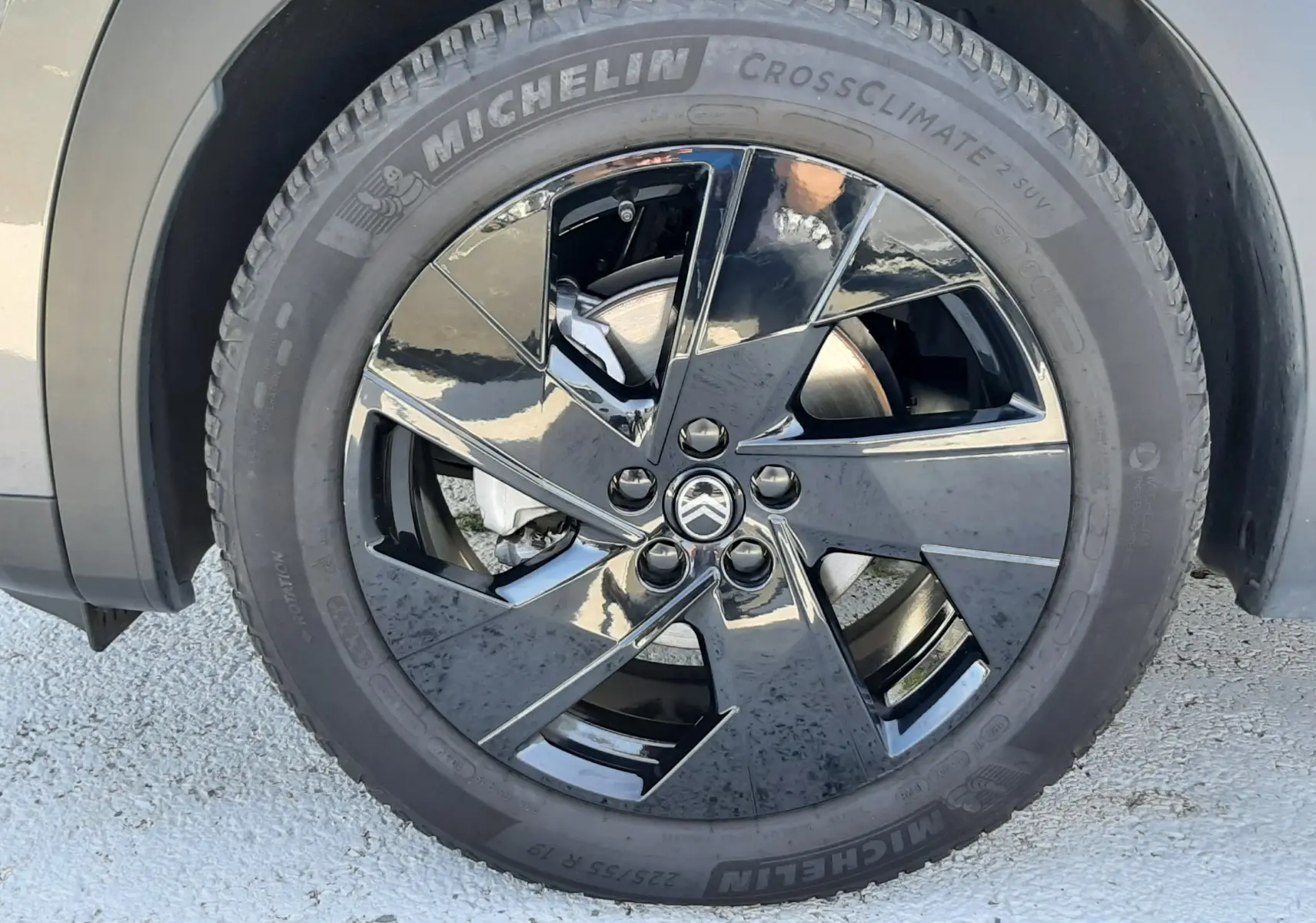 Gros plan sur la roue avant droite du Citroën C5 Aircross gris platinium, jante alliage noire brillante avec logo Citroën central.