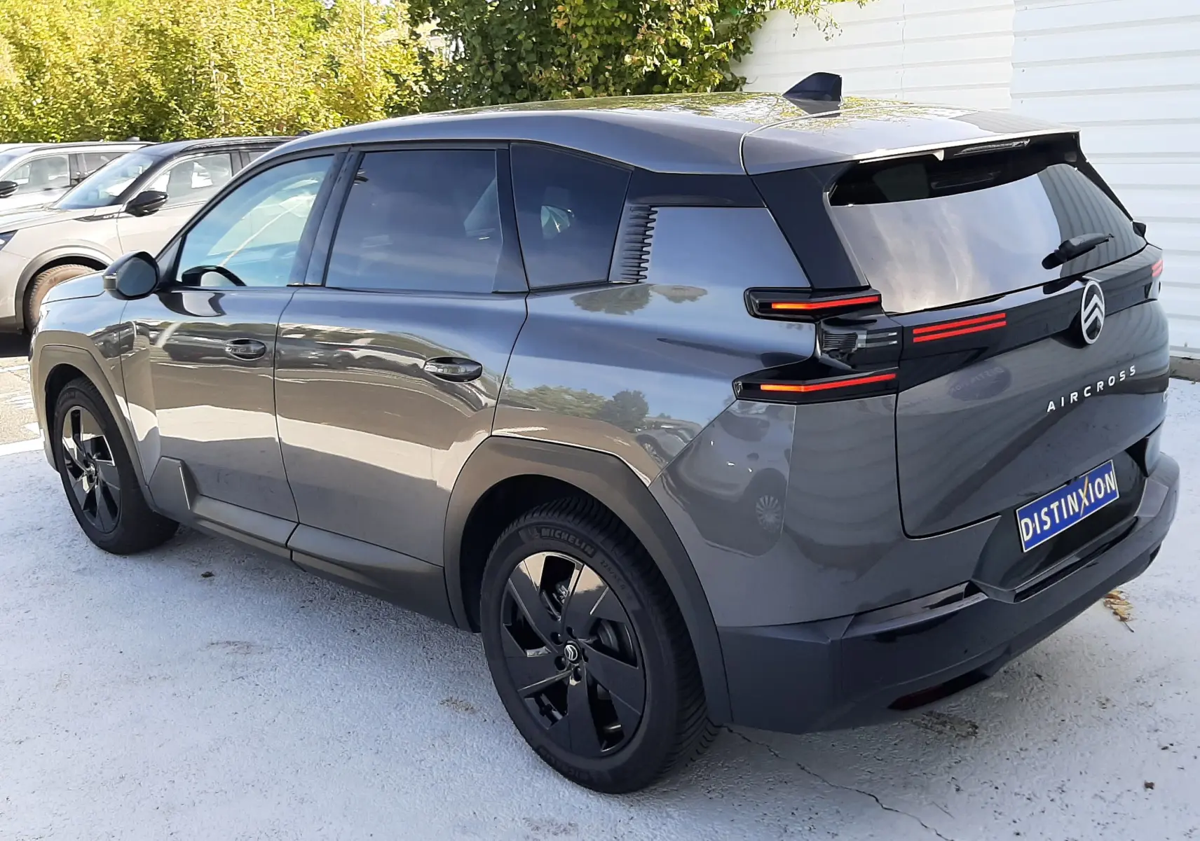 Vue 3/4 arrière droite d'un Citroën C5 Aircross Hybride gris platinium avec feux arrière LED et jantes noires.