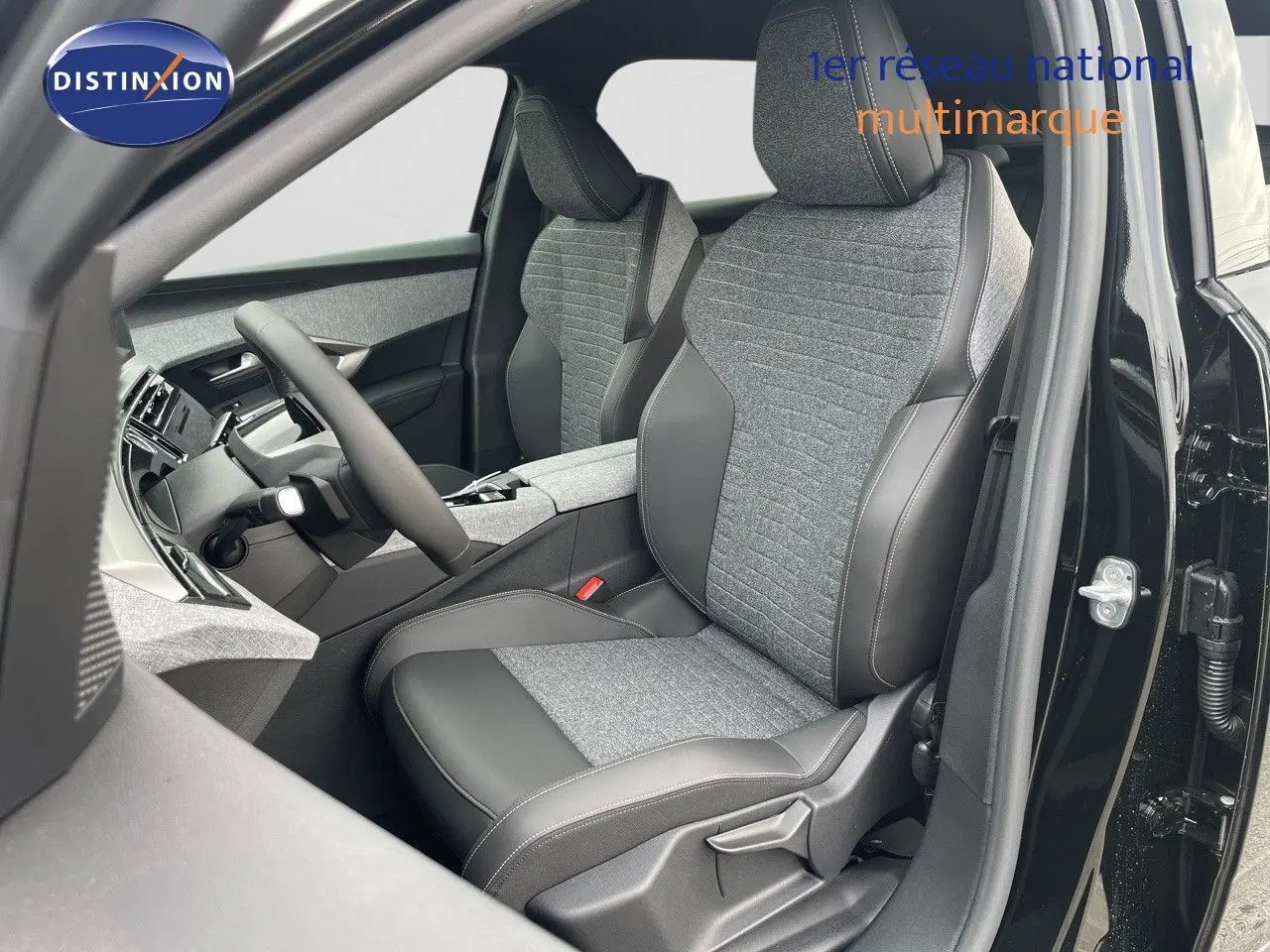 Intérieur du Peugeot 3008 Hybrid 2025, vue côté conducteur avec sièges bi-matière gris et noir perle métal extérieur visible.