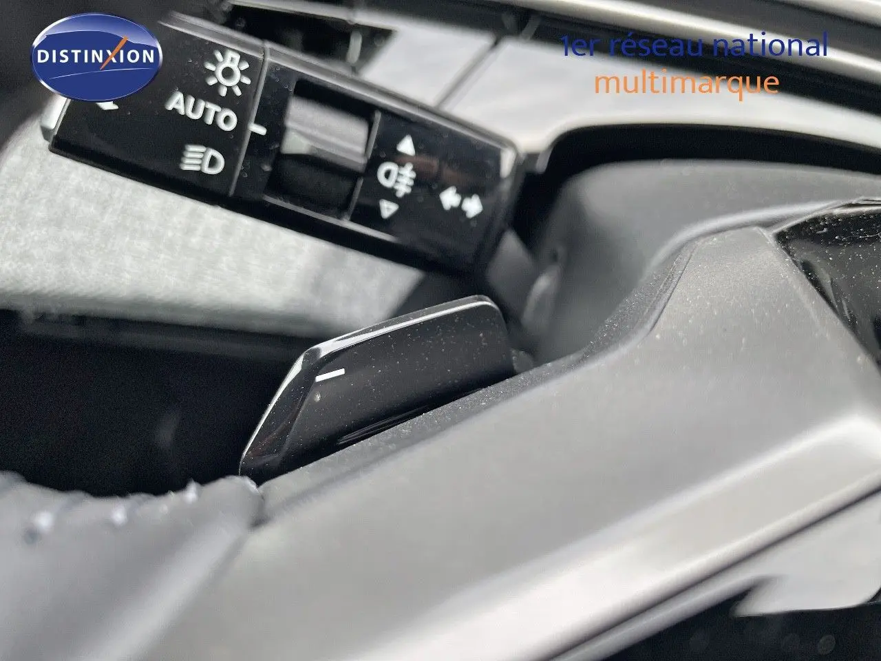 Gros plan sur la commande de feux et le levier de vitesses d'une Peugeot 3008 Hybrid noir perle métal, intérieur moderne.
