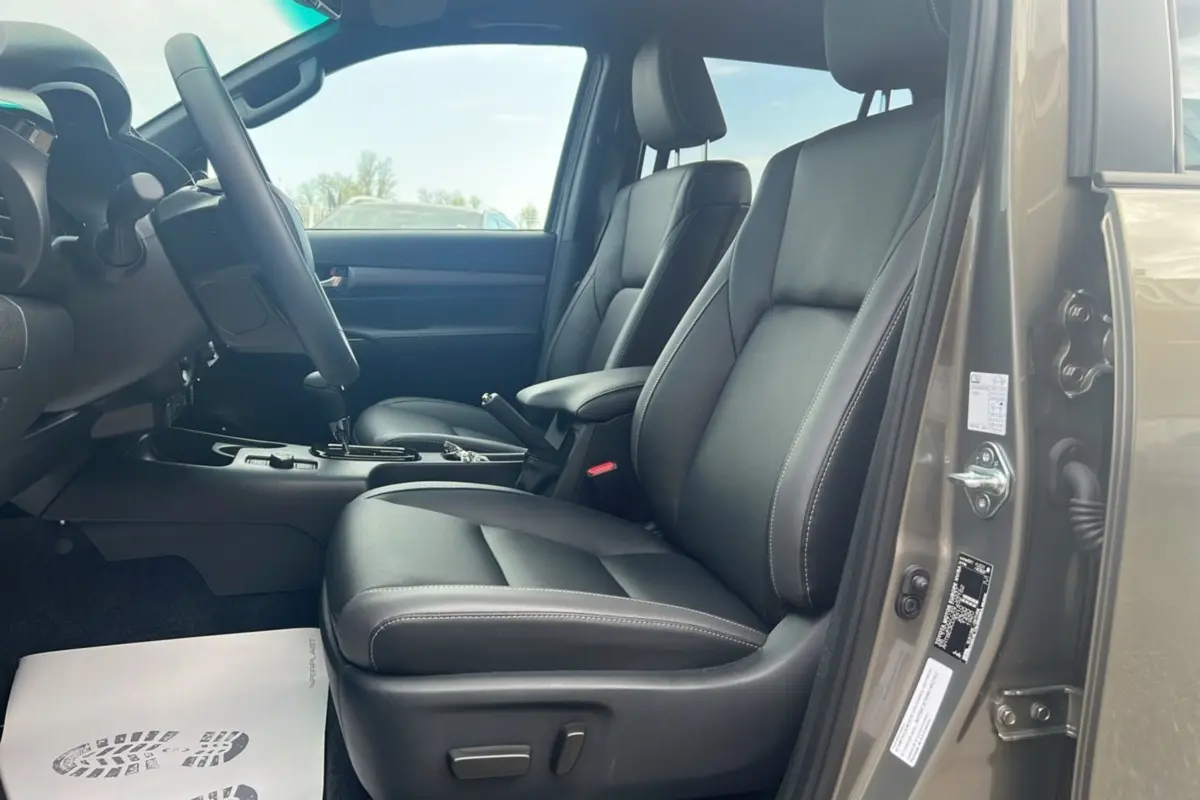 Vue intérieure côté conducteur du Toyota Hilux 2025 en bronze impérial, sièges en cuir noir et console centrale visible.