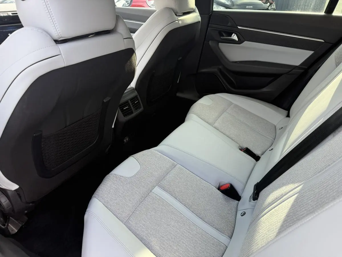 Vue intérieure arrière de la Peugeot 508 avec sièges bi-matière gris clair et aérateurs centraux visibles.